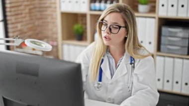 Klinikte bilgisayar kullanan genç sarışın kadın.