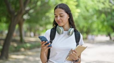 Parkta akıllı telefon rehberi kullanan Afrikalı Amerikalı bir kız öğrenci.