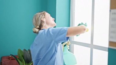 Ofiste gülümseyen genç sarışın profesyonel temizlikçi kadın.