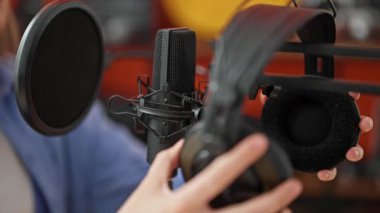 Genç sarışın kadın müzisyen müzik stüdyosunda şarkı söylüyor.