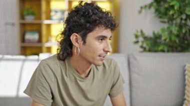 Kanepede oturan İspanyol genç adam konuşuyor.