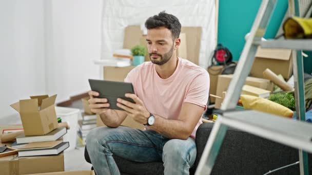Young Hispanic Man Using Touchpad Sitting Sofa New Home — 图库视频影像