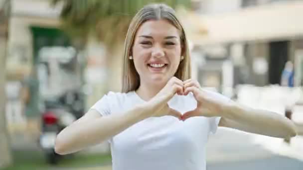 Young Blonde Woman Smiling Confident Doing Heart Gesture Hands Street — Stockvideo