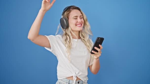 Mujer Rubia Joven Escuchando Música Bailando Sobre Fondo Azul Aislado — Vídeos de Stock