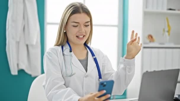 年轻的金发女医生在诊所用智能手机做视频通话 — 图库视频影像