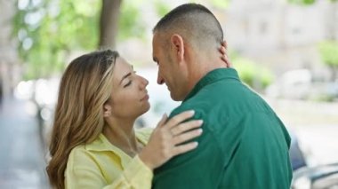 Man and woman couple hugging each other kissing at street