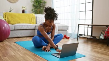 Afrikalı Amerikalı kadın evde yoga dersi alıyor.