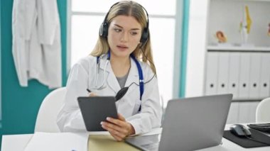 Videodaki sarışın kadın doktor klinikteki touchpad 'e yazı yazıyor.