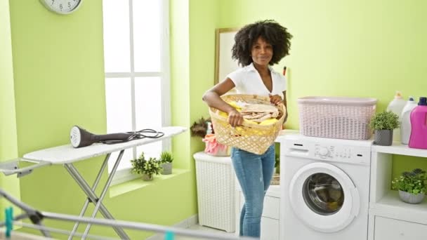 Afroamerikanerin Lächelt Selbstbewusst Und Hält Korb Mit Kleidern Der Waschküche — Stockvideo