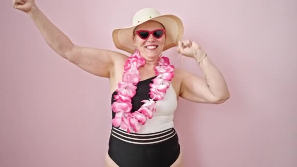 Седовласая Туристка Средних Лет Купальнике Гавайских Леях Танцует Изолированном Розовом — стоковое видео