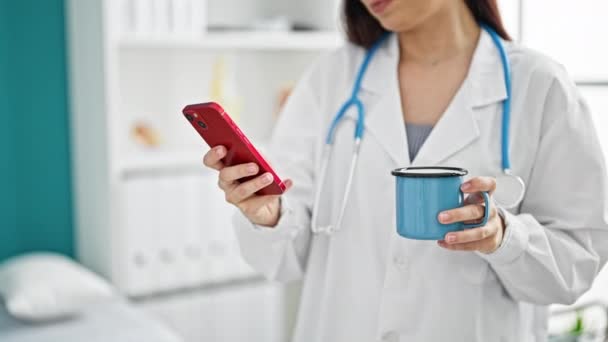 Νεαρή Όμορφη Ισπανίδα Γιατρός Χρησιμοποιώντας Smartphone Πίνοντας Καφέ Στην Κλινική — Αρχείο Βίντεο