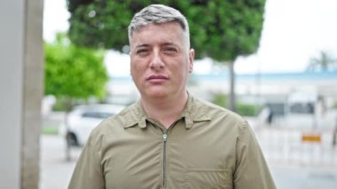 Kafkasyalı genç adam ciddi bir ifadeyle ayakta duruyor ve kafası sokaklardayken 