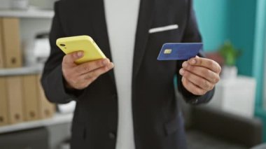 Genç Arap iş adamı akıllı telefon ve kredi kartıyla alışveriş yapıyor.