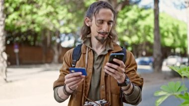 Genç İspanyol turist akıllı telefon ve kredi kartıyla parkta alışveriş yapıyor.