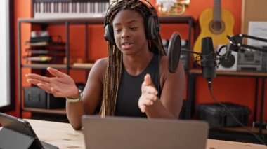 Afrikalı Amerikalı kadın muhabir müzik stüdyosunda radyo programı yapıyor.