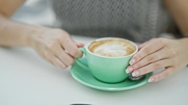 Kahve dükkanının terasında bir fincan kahve içen genç sarışın kadın.