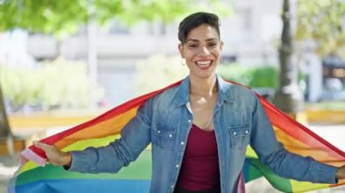 Parkta gökkuşağı bayrağı takan kendine güvenen güzel İspanyol kadın.