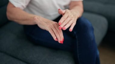 Orta yaşlı bir kadın eve losyon sürüyor.