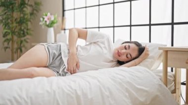 Genç ve güzel İspanyol kadın adet sancısı çekiyor. Yatak odasında uzanmış yatıyor.