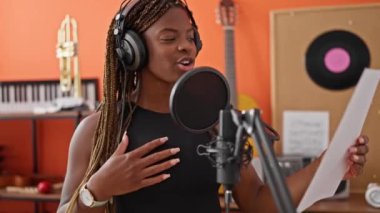 Afrikalı Amerikalı kadın müzisyen gülümsüyor. Müzik stüdyosunda kendine güvenen şarkı söylüyor.