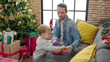 Baba oğul Noel 'i evde oyuncaklarla oynayarak kutluyorlar.
