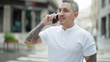 Genç İspanyol adam gülümsüyor. Kendine güveniyor. Sokakta akıllı telefondan konuşuyor.