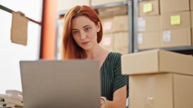 Genç kızıl saçlı kadın iş kadını. Ofise dizüstü bilgisayar kullanarak bakıyor.