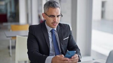 Genç İspanyol iş adamı akıllı telefon kullanıyor. Ofise üzgün bakıyor.