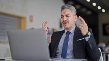 Genç İspanyol iş adamı ofiste diz üstü bilgisayar kullanarak birinci sınıf bir jest yapıyor.