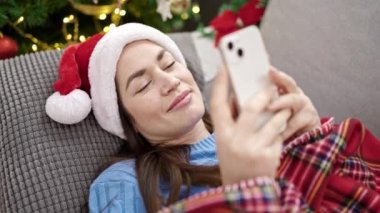 Beyaz bir kadın evde akıllı telefon kullanarak Noel 'i kutluyor.