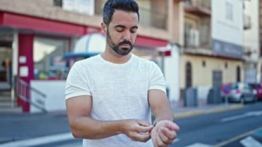 Sokakta saat takan ciddi yüzlü İspanyol bir genç.