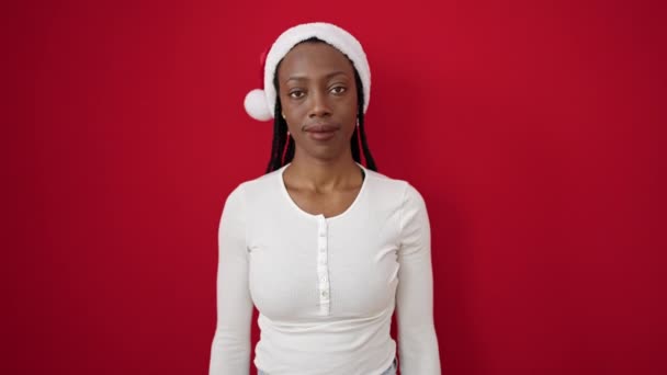 Mujer Afroamericana Sonriendo Confiada Usando Sombrero Navidad Sobre Fondo Rojo — Vídeos de Stock