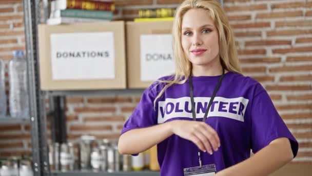 Молодая Блондинка Волонтер Улыбается Уверенно Стоя Скрещенными Руками Благотворительном Центре — стоковое видео