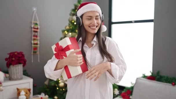 年轻美丽的惊慌失措的女人在家里听着带着圣诞礼物的音乐 — 图库视频影像
