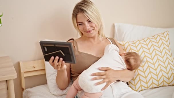 Mãe Filha Sentadas Cama Amamentando Bebê Olhando Foto Quarto — Vídeo de Stock