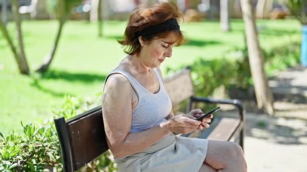 Mujer Mediana Edad Con Teléfono Inteligente Con Expresión Seria Sentado — Vídeos de Stock