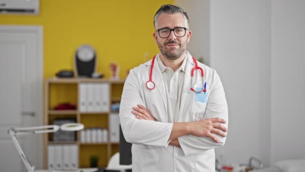 Gri Saçlı Doktor Gülümsüyor Kollarını Kavuşturup Klinikte Duruyormuş — Stok video