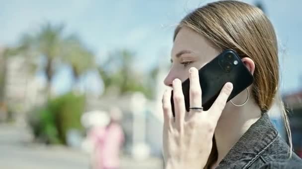 年轻的金发女人在街上用智能手机严肃地说话 — 图库视频影像