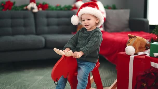 愛らしいブロンド幼児遊びますともにトナカイロッキングによってクリスマスツリーホーム — ストック動画