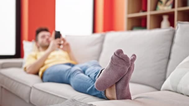 年轻人用智能手机躺在家里的沙发上 — 图库视频影像