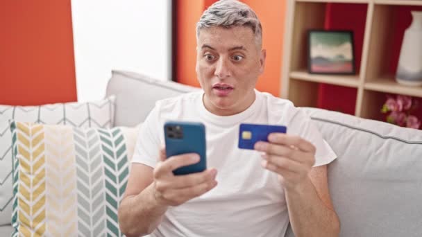 Jonge Kaukasische Man Winkelen Met Smartphone Creditcard Kijken Boos Thuis — Stockvideo