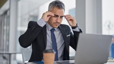 Ofiste dizüstü bilgisayar kullanarak gözlük takan İspanyol bir iş adamı.