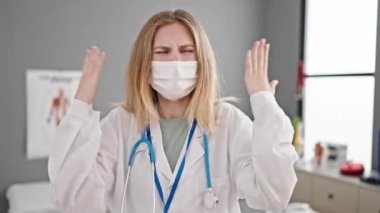 Tıbbi maske takan genç sarışın kadın kliniğe kızgın ve bağırıyor.