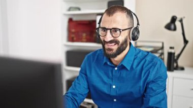 Genç İspanyol iş adamı ofiste bilgisayar ve kulaklık kullanıyor.