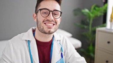 Genç İspanyol doktor klinikte kendinden emin gülümsüyor.