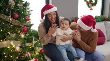 Çift ve oğul evde Noel ağacı süslüyorlar.