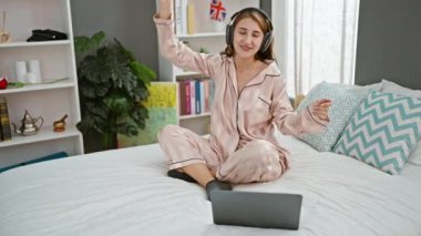Yatak odasında müzik dinleyen genç bir kadın.