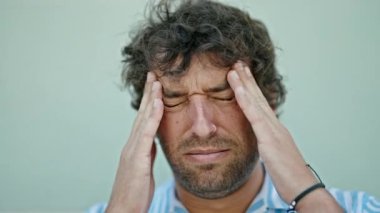 Genç İspanyol adam izole edilmiş beyaz arka plan yüzünden baş ağrısı çekiyor.