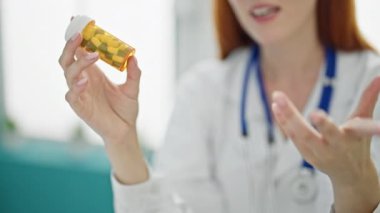 Genç kızıl saçlı kadın doktor klinikte reçete yazıyor.