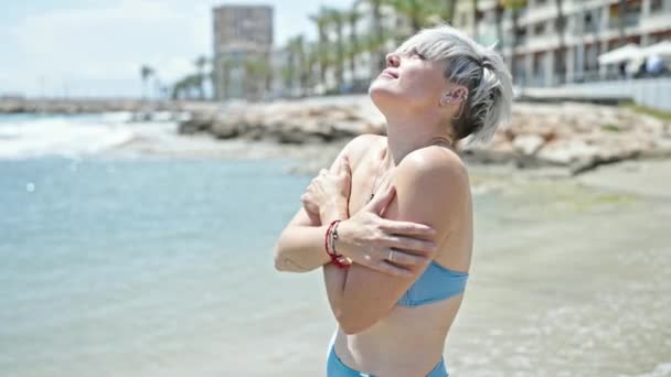 穿着比基尼的年轻女性游客在海滩上拥抱自己 — 图库视频影像